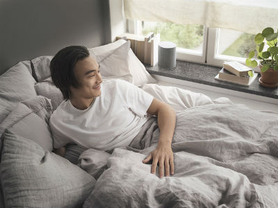 Man in bed with Beoplay M3 on bedside ledge