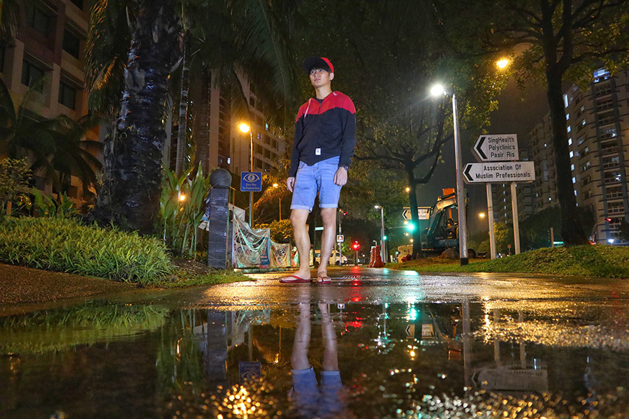 Man standing on street with puddle reflection