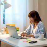 Candid of happy young attractive asian woman work at home in evening or late night with SME business owner, young entrepreneur or freelance concept. Young asian student study online in self education.