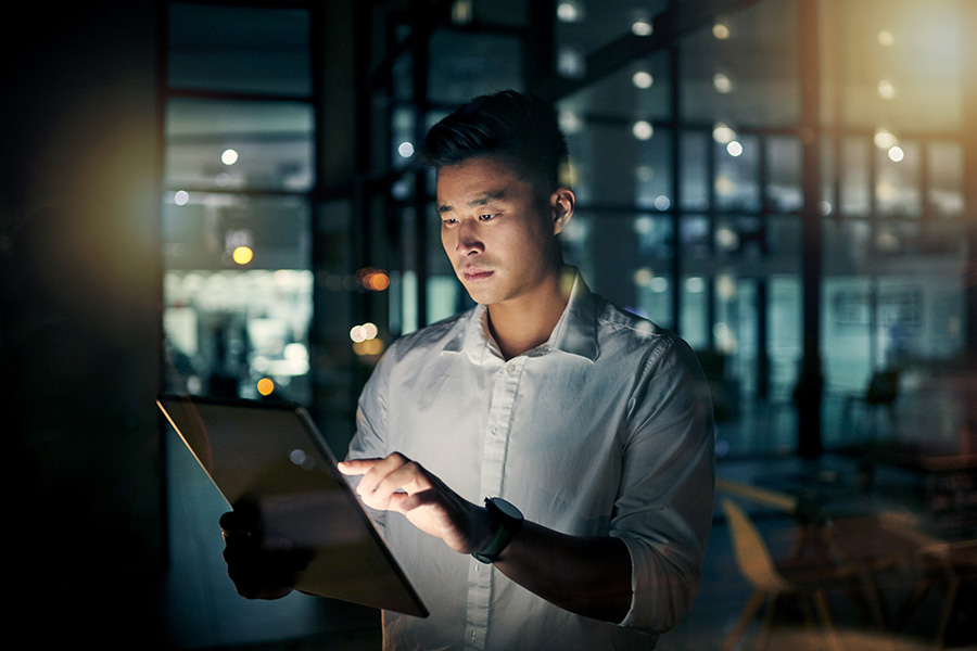 Shot of a young businessman using a digital tablet during a late night in a modern office